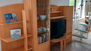 A room with a wooden cabinet containing books and a television. - Vacation home Kleine Einkehr - comfortable & quiet in Waren (Müritz), with balcony (Waren (Müritz))
