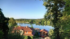 A lakeside property with multiple buildings, a red car, and lush greenery. - Vacation home Kleine Einkehr - comfortable & quiet in Waren (Müritz), with balcony (Waren (Müritz))