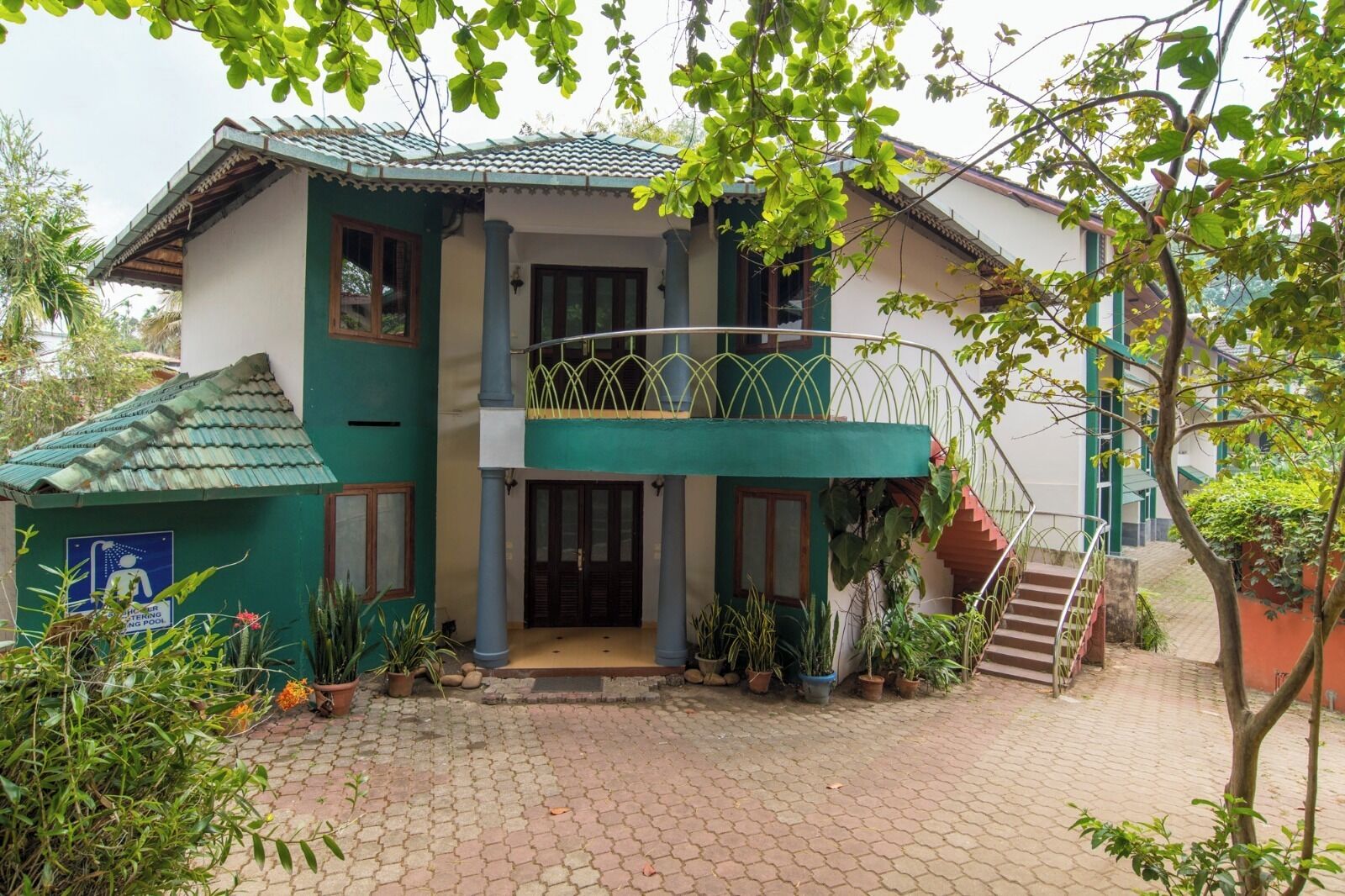 A two-story house with a balcony, a staircase, and potted plants.
