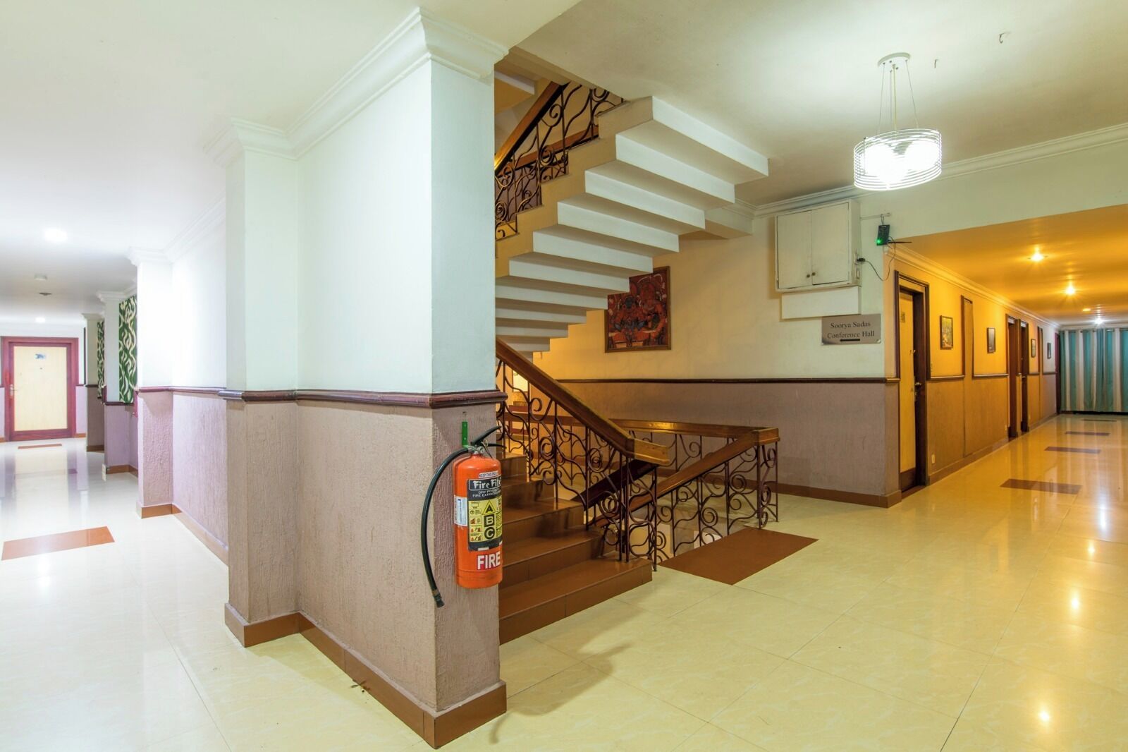 A hotel lobby with a modern staircase, a fire extinguisher, and a sign indicating a conference hall.