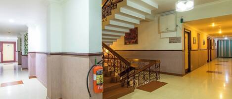 A hotel lobby with a modern staircase, a fire extinguisher, and a sign indicating a conference hall.