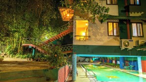 A hotel with a swimming pool, outdoor stairs, and potted plants. - Harithagiri Hotel (Kalpetta)