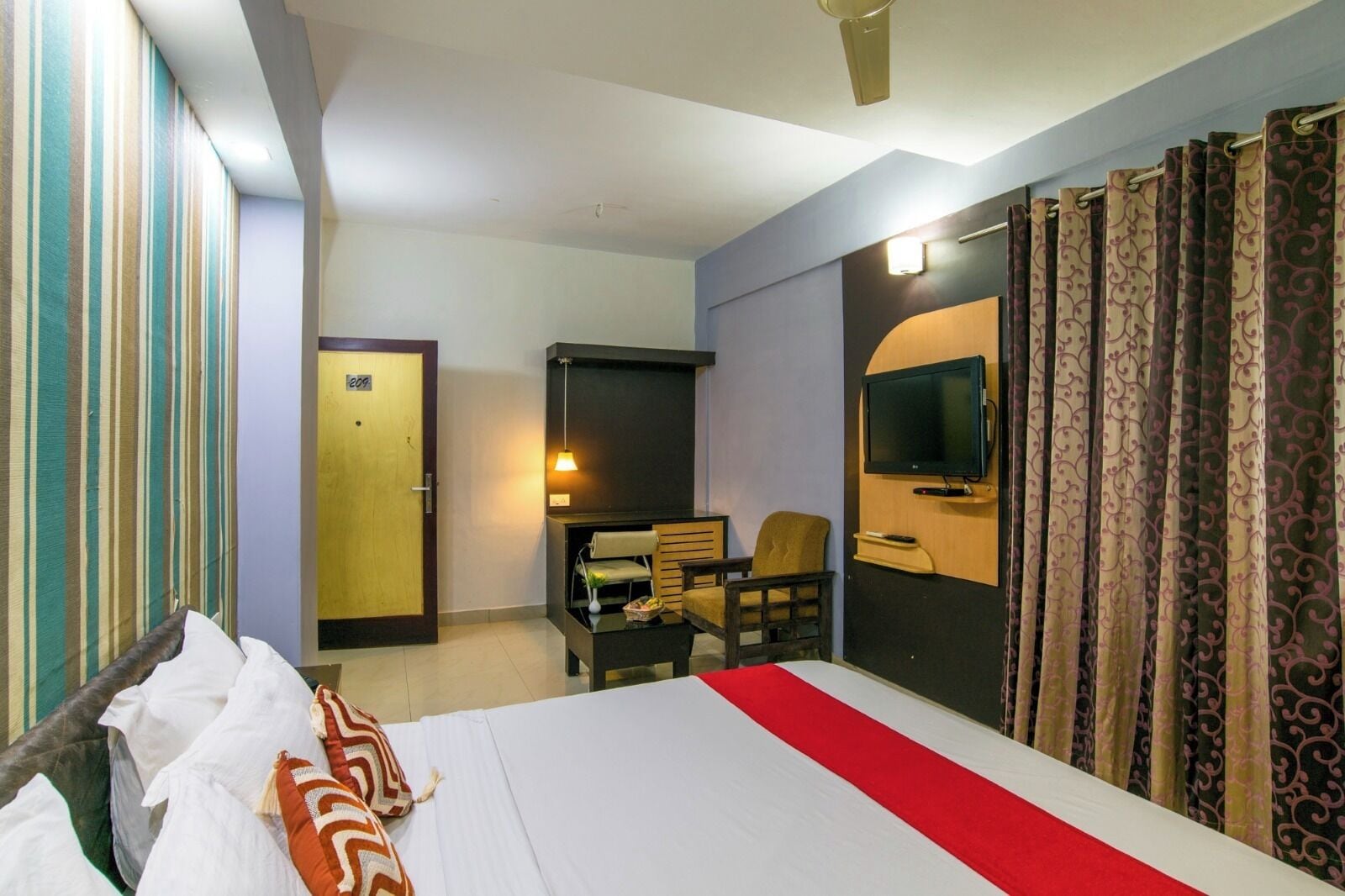 Una habitación de hotel con cama, escritorio, silla, televisor y puerta.
