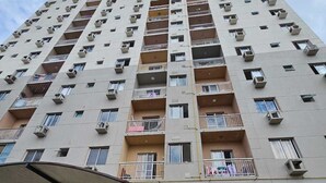 A high-rise residential building with multiple balconies, a covered entrance, and a parking area with a car and a motorcycle. - COP30 Apartment - Total Life Condominium (Tenoné Belém)