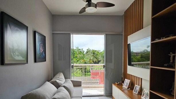 A modern living room with a sofa, a dining table with yellow chairs, a ceiling fan, and a TV on a wooden shelf. - COP30 Apartment - Total Life Condominium (Tenoné Belém)