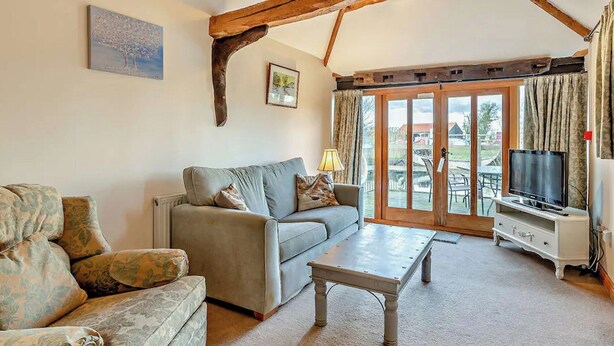 A cozy living room with a sofa, a coffee table, and a television. - Pond View Cottage - UK48230 (Tibenham)