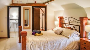 A bedroom with a bed, wooden headboard, bedside tables, and a mirror. - Pond View Cottage - UK48230 (Tibenham)