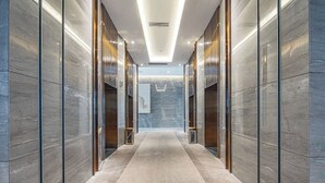 A modern hallway with marble walls and a glass elevator. - Changde Licheng Huating Hotel (Changde)