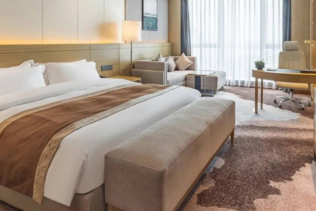 A hotel room with a large bed, a desk, a chair, and a sofa.