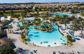 Un resort con varias piscinas, palmeras y áreas de descanso.