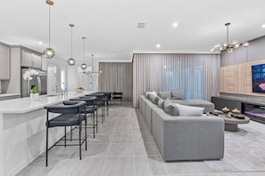 Una cocina moderna con una isla central, taburetes de bar e iluminación colgante.