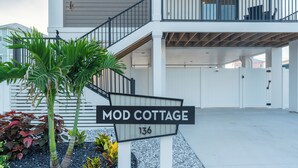 A residential property named 'Mod Cottage' with a staircase leading to a balcony, surrounded by tropical plants. - 🏝️ Mod Cottage | 5 BR Home | 2 Minute Walk to the Beach | Private Pool 🌊 (Fort Myers Beach)