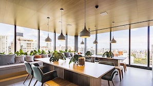 Un intérieur moderne avec une table centrale faisant office d’îlot, des sièges et de grandes fenêtres offrant une vue sur la ville.