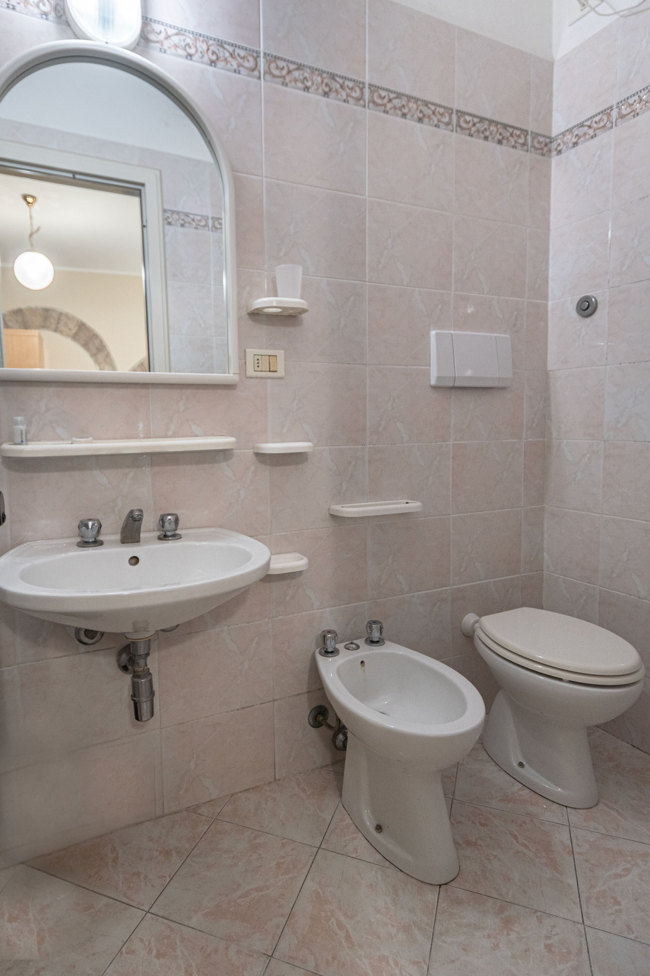 A bathroom with a sink, bidet, and toilet.