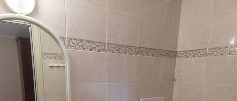 A bathroom with a sink, bidet, toilet, mirror, and a showerhead.