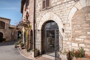 Un edificio in pietra con un'ampia porta ad arco, piante in vaso e un'insegna che indica un ristorante.
