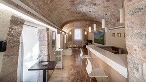 Interior com paredes de pedra, área de bar, assentos e tela de projeção.