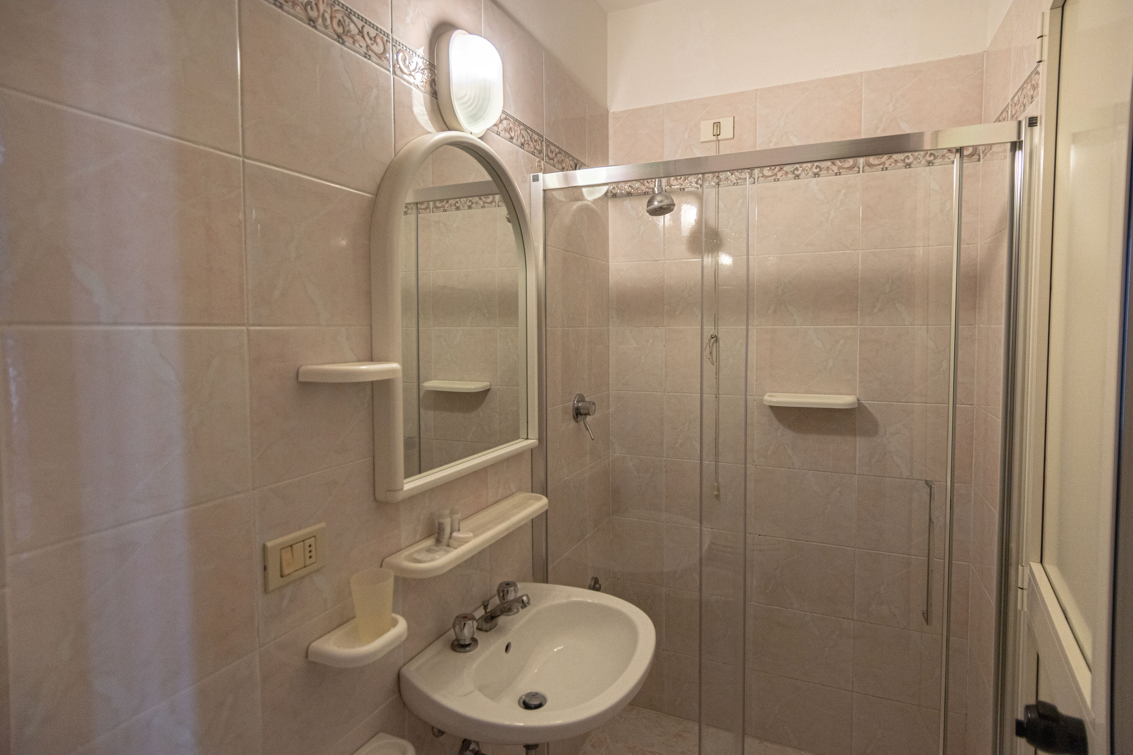 A bathroom with a sink, mirror, and shower enclosure.