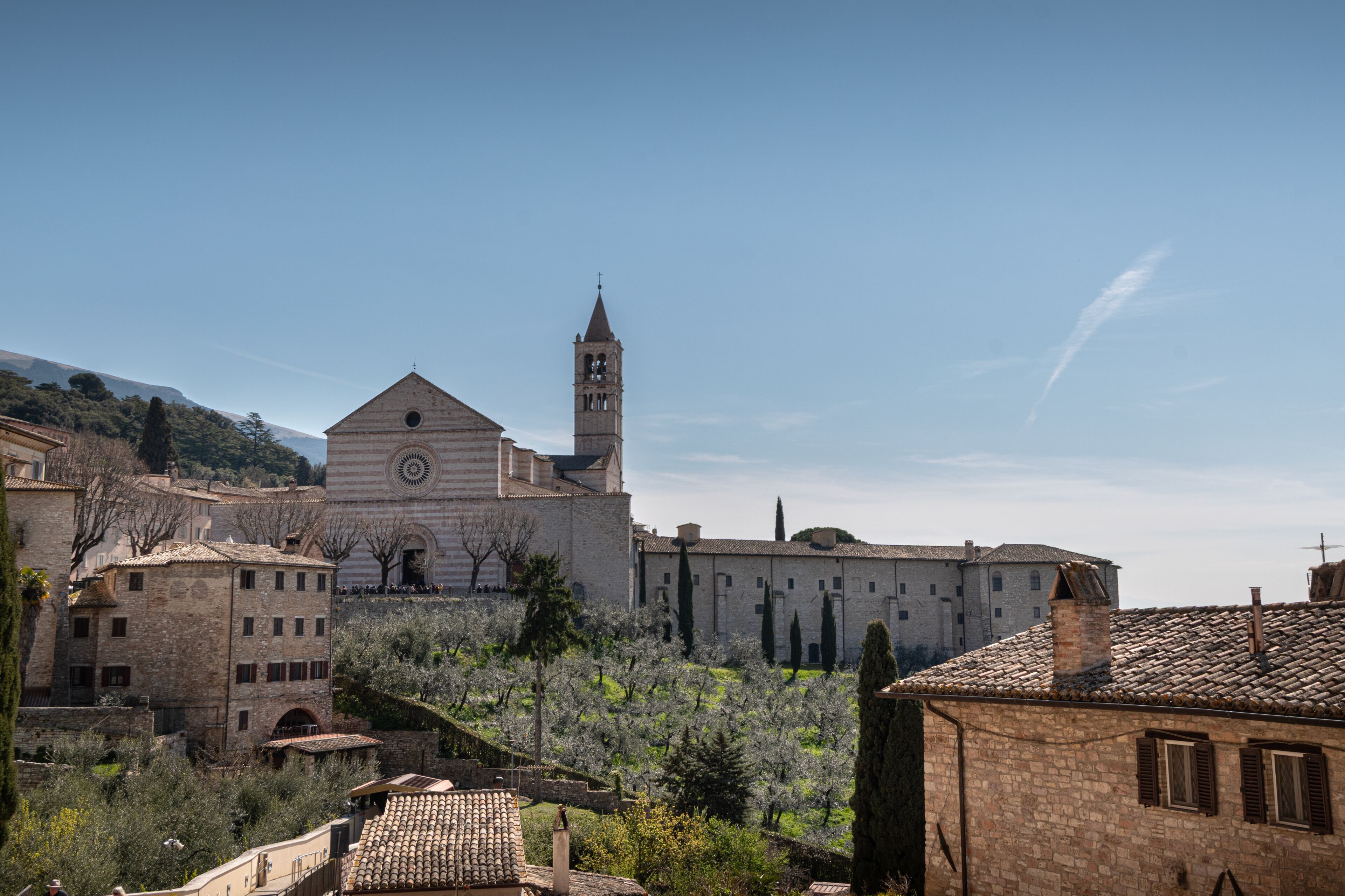 A historic building with a bell tower, surrounded by traditional stone buildings and lush greenery.