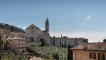 A historic building with a bell tower, surrounded by traditional stone buildings and lush greenery.