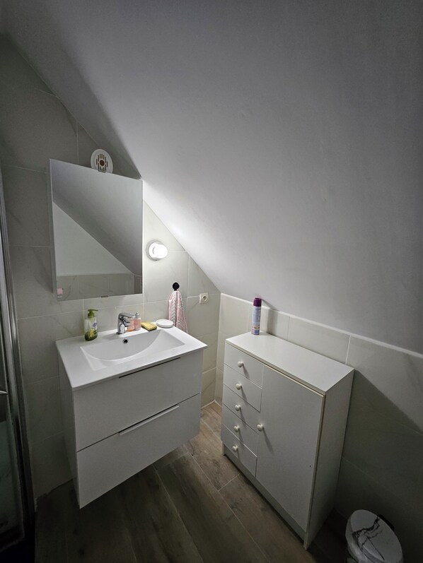 A modern bathroom with a white vanity, a mirror, and a toilet. - Penty in a quiet traditional village (Crozon)