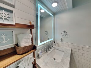 A modern bathroom with a wooden vanity, a large mirror, a sink, and a towel rack.