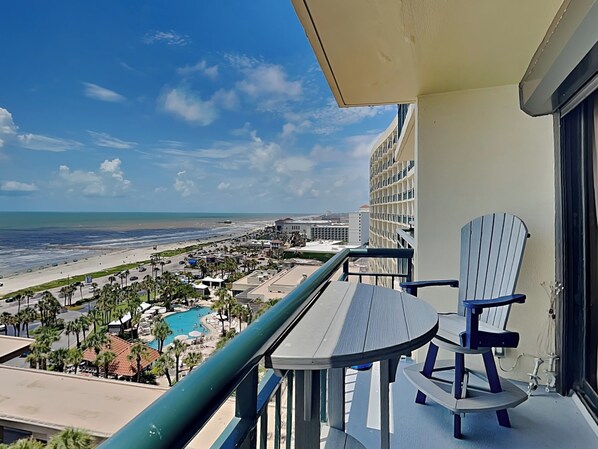 A balcony with a view of a beach and a pool.