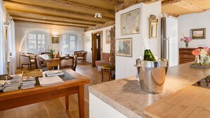 A spacious room with wooden beams, a dining area with chairs, a kitchen counter, and a refrigerator. - Holiday Home 'Zur Alten Dame' with Mountain Views, Private Garden & Wi-Fi (Badenweiler)