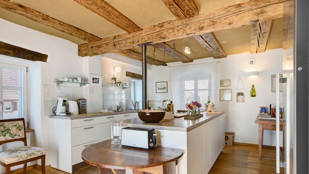 A kitchen with wooden beams, a central island, a toaster, and a chair. - Holiday Home 'Zur Alten Dame' with Mountain Views, Private Garden & Wi-Fi (Badenweiler)