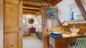 A rustic room with exposed wooden beams, a desk with a lamp, a chair, a bed, and a painting on the wall. - Holiday Home 'Zur Alten Dame' with Mountain Views, Private Garden & Wi-Fi (Badenweiler)