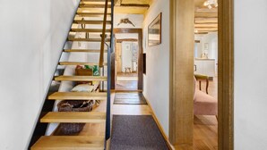 A wooden staircase leading to a room with a bed, a chair, and a small table. - Holiday Home 'Zur Alten Dame' with Mountain Views, Private Garden & Wi-Fi (Badenweiler)