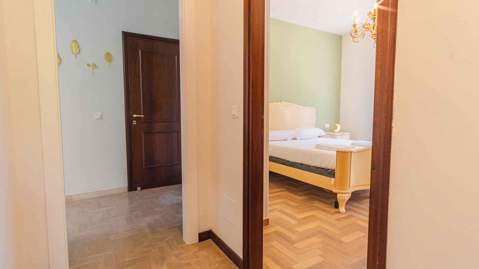 Un dormitorio con una cama de madera, una mesita de noche y una lámpara fijada a la pared.