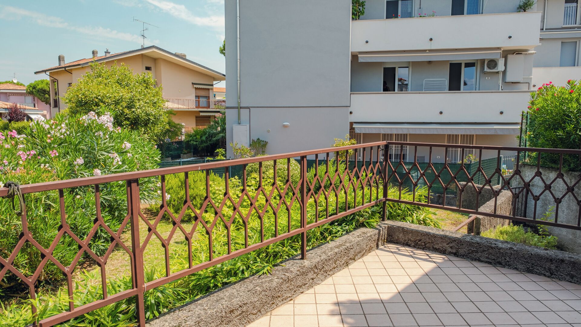Un quartier résidentiel doté de balcons grillagés, d’une terrasse carrelée et de bâtiments adjacents.