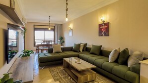 A modern living room with a sectional sofa, a coffee table, and a TV on a wall. - Top localisation, neuf, Piscine et une vue balcon (Marrakesh)