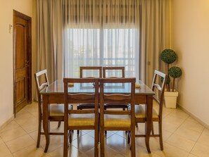 A dining area with a wooden table and chairs, a potted plant, and a door. - Top localisation, neuf, Piscine et une vue balcon (Marrakesh)