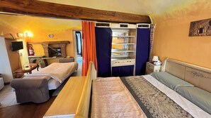 Une pièce confortable avec un lit, un bureau et une chaise. On y trouve également une cheminée et un téléviseur.