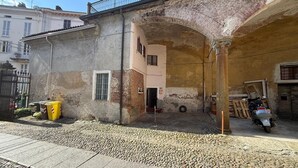 Un bâtiment doté d’une façade en pierre, d’un balcon en métal et d’une cour pavée où sont entreposés des matériaux de construction.