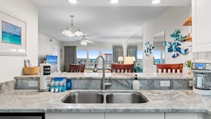 A modern kitchen with a marble countertop, double sink, and a coffee maker.