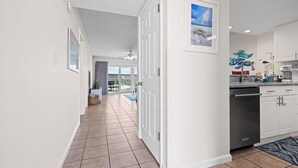 A modern kitchen with white cabinets, a dishwasher, and a blue rug.