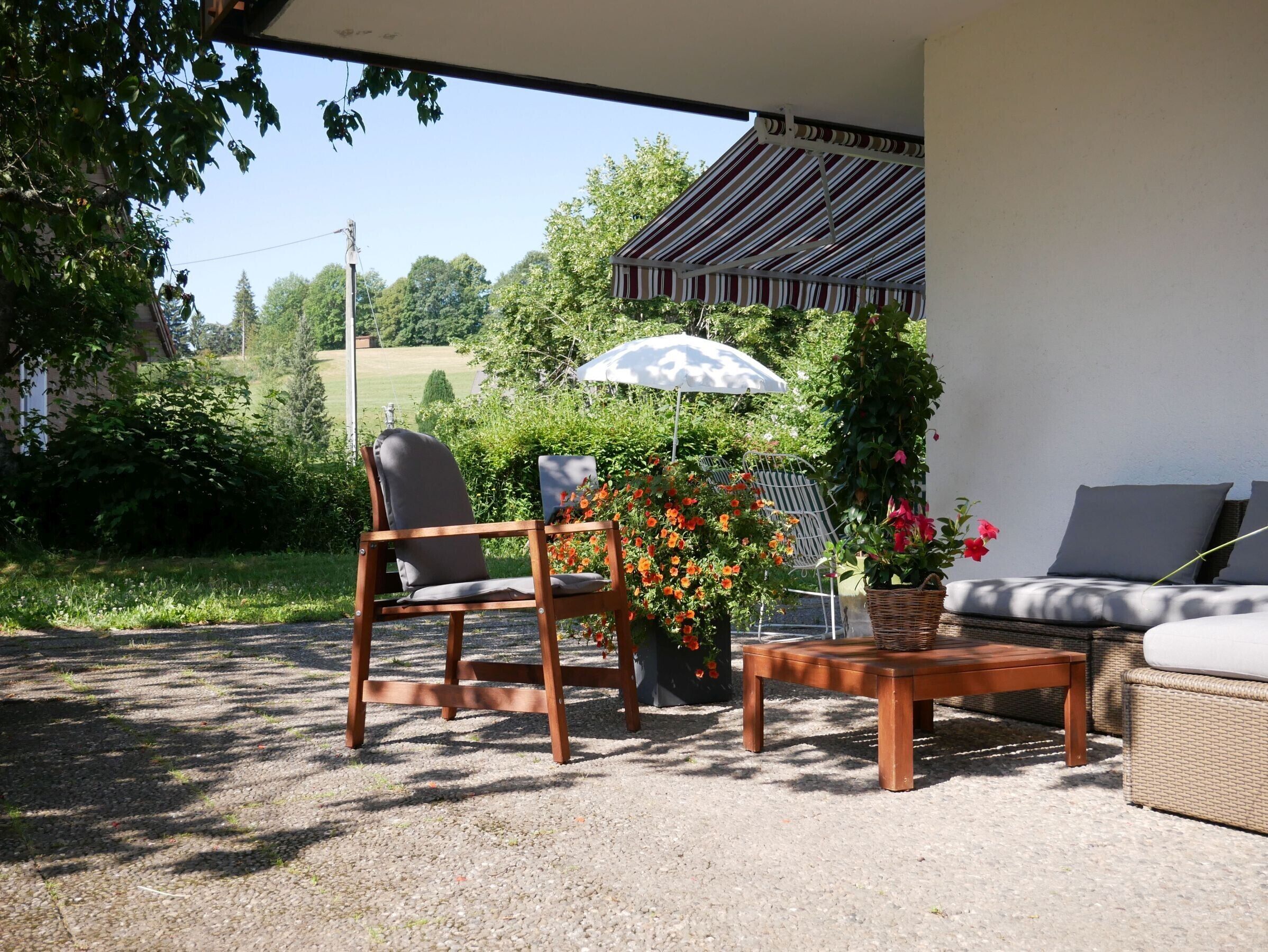 An outdoor seating area with a table, chairs, and a covered patio.