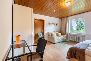 Une chambre moderne avec une table en verre, un canapé, un lit et un plafond en bois.