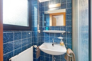 A bathroom with blue tiles, a white sink, a mirror, and a window. - Room 'Single Room - No. 8 with Separate WC' with Shared Terrace and Shared Garden (Dachsberg)