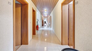 A hallway with wooden doors, a fire extinguisher, and a ceiling light fixture. - Room 'No. 7' with Shared Terrace and Shared Garden (Dachsberg)