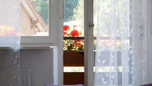A bedroom with a bed, a window with a view of a garden, and a door. - Apartment 'No. 3' with Shared Terrace, Shared Garden and Balcony (Dachsberg)