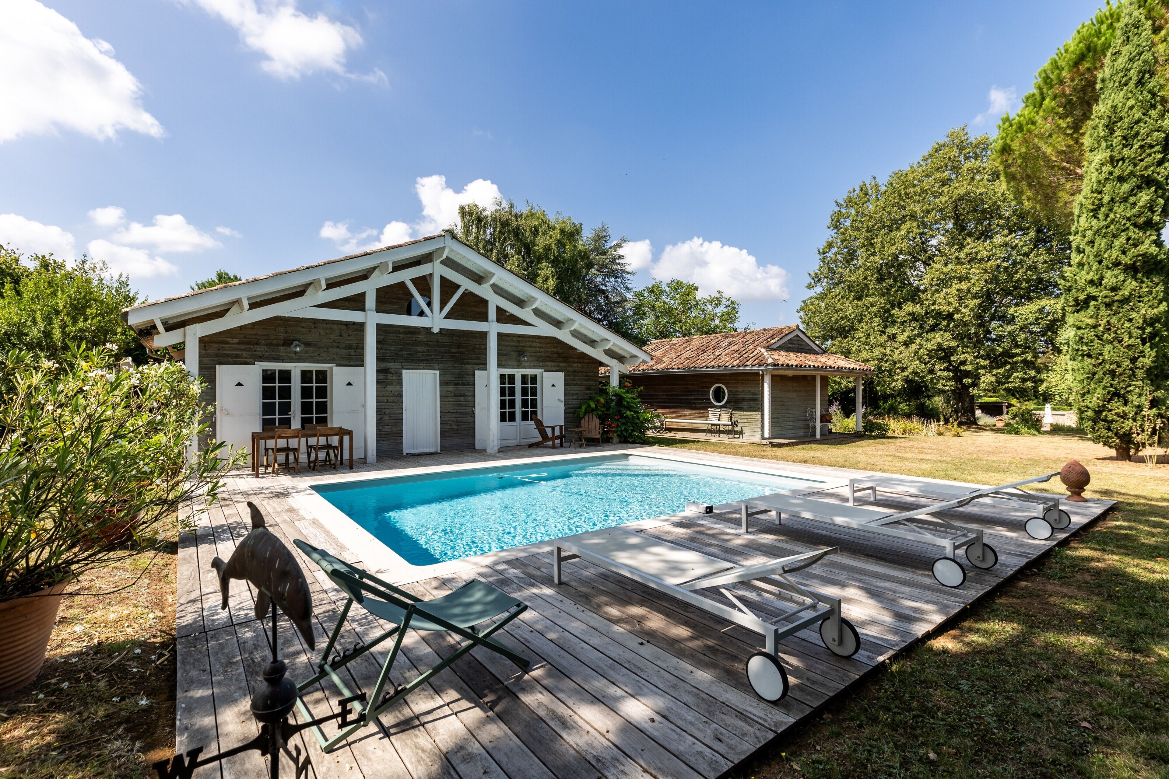 Una terraza de madera con piscina, sillas de descanso y un jacuzzi.