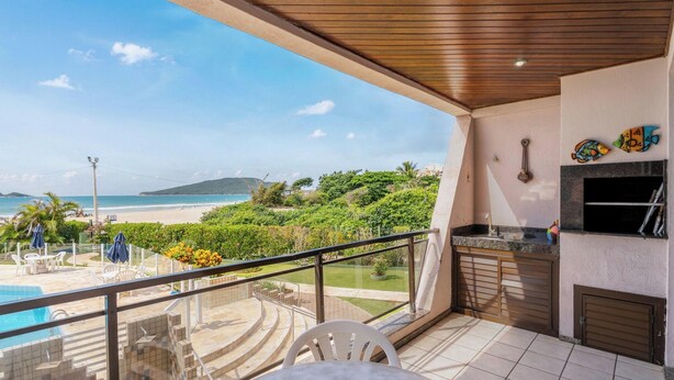 Un balcone con vista sulla spiaggia e sulla piscina, dotato di barbecue e mobili da esterno.