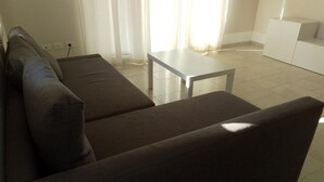 A modern living room with a dark brown sofa, a small white table, and a white cabinet. - Apartment 'Florida 2' with Sea View, Wi-Fi and Air Conditioning (San Teodoro)