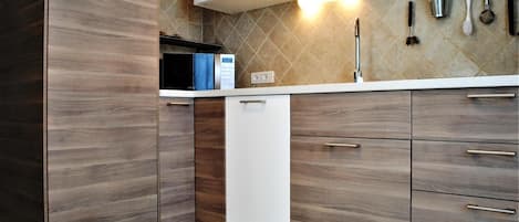 A modern kitchen with wooden cabinets, a white dishwasher, and a tiled backsplash.
