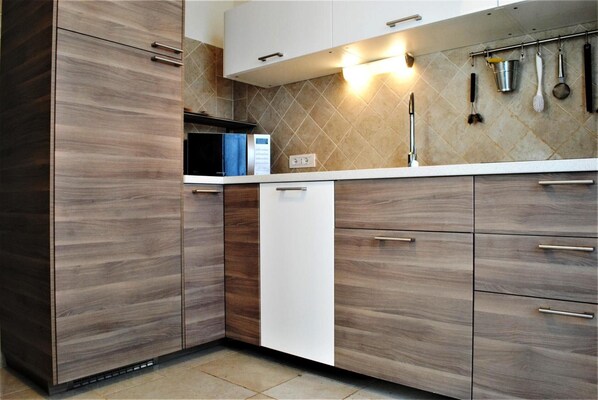 A modern kitchen with wooden cabinets, a white dishwasher, and a tiled backsplash.