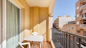 Un balcon avec une table et des chaises, une vue sur la rue et un immeuble doté de balcons.